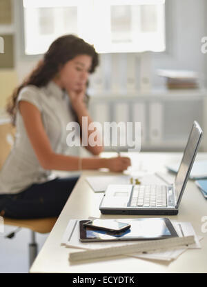 Close up of cell phone, digital tablet and laptop on desk of mixed race businesswoman Stock Photo