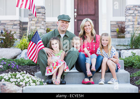 Caucasian soldier and family smiling together on front stoop Stock Photo