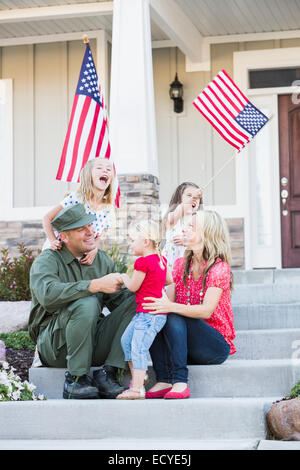 Caucasian soldier and family playing together on front stoop Stock Photo