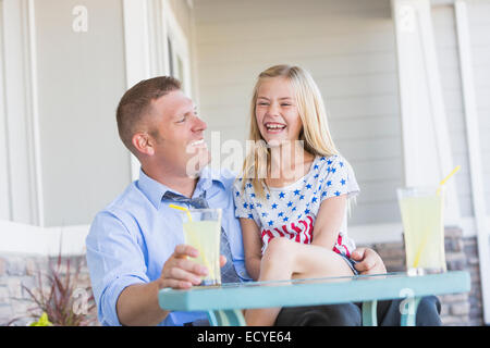 Caucasian father and daughter laughing on porch Stock Photo