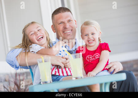 Caucasian father and daughters laughing on porch Stock Photo
