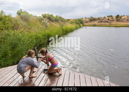 Sisters playing together on wooden dock near lake Stock Photo