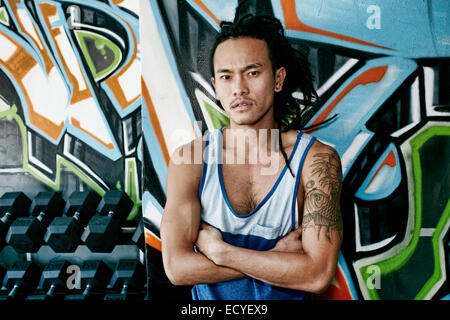 Asian man standing with arms crossed in gym Stock Photo