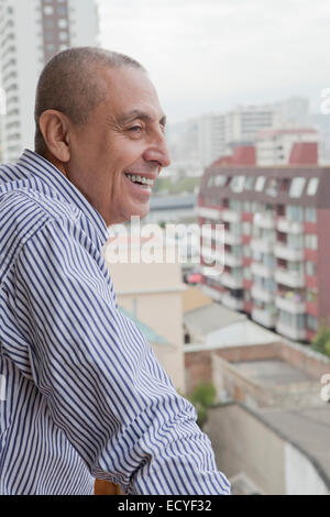 Hispanic senior man admiring cityscape from balcony Stock Photo