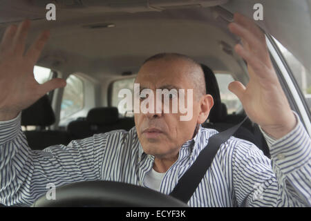 Frustrated Hispanic senior man driving car in traffic Stock Photo