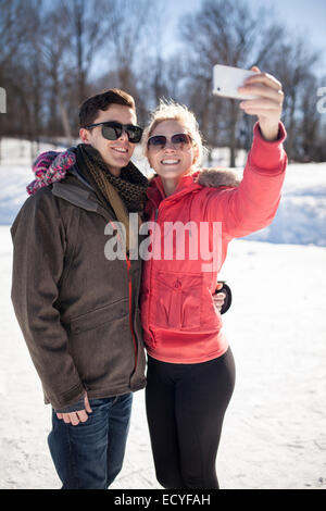 Caucasian couple taking cell phone selfie in winter Stock Photo