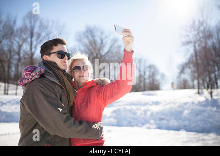 Caucasian couple taking cell phone selfie in winter Stock Photo