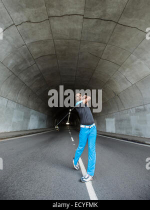 Black man playing golf in urban tunnel Stock Photo