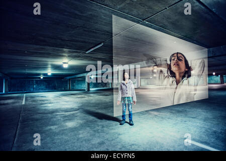 Mixed race girl watching holographic screen in parking lot Stock Photo