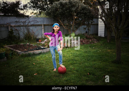 Mixed race girl playing with soccer ball in backyard Stock Photo
