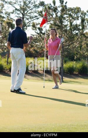 Caucasian couple playing golf on course Stock Photo