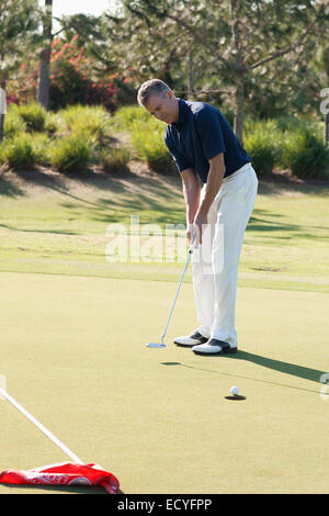 Caucasian man putting on golf course Stock Photo