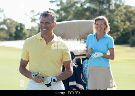 Caucasian couple playing golf on course Stock Photo