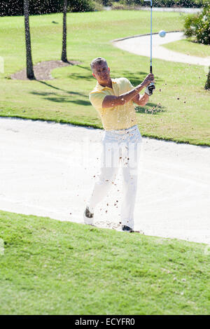 Caucasian man golfing from sand trap on golf course Stock Photo