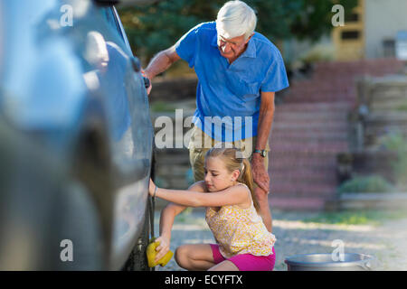 Caucasian grandfather and granddaughter washing car outdoors Stock Photo