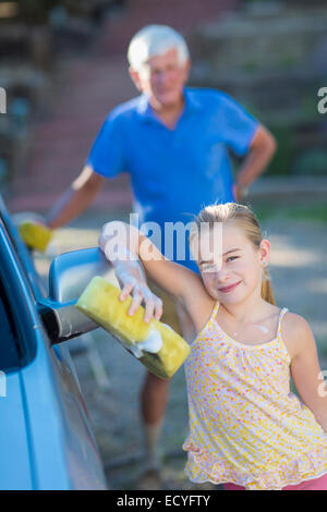 Caucasian grandfather and granddaughter washing car outdoors Stock Photo