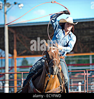 Caucasian cowgirl on horse throwing lasso in rodeo on ranch