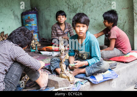 Boys polising Buddhist statues in Kathmandu, Nepal Stock Photo