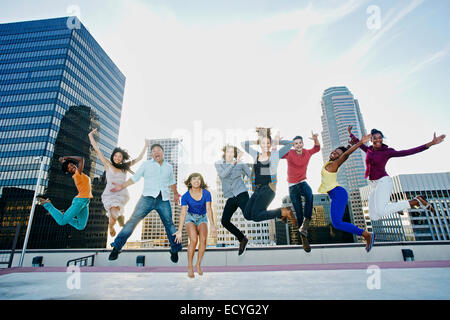 Friends jumping for joy on urban rooftop Stock Photo