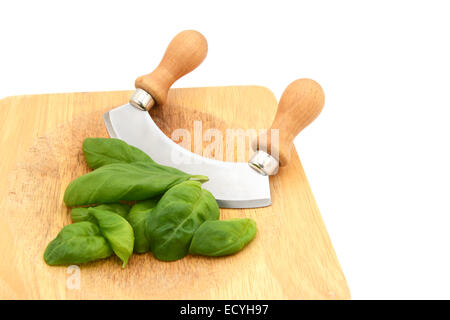 Fresh basil leaves with a rocking knife on a wooden chopping board, isolated on a white background Stock Photo