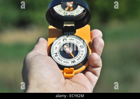 Compass in hand. The magnetic compass lies in a man's hand on a background of nature. Stock Photo