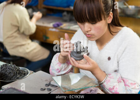 Woman at Terracotta warrior factory working on a sculpture of a baby dragon in Xi'an, China Stock Photo