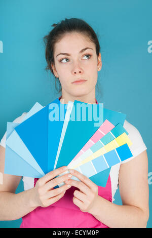 Woman with color samples against blue wall Stock Photo