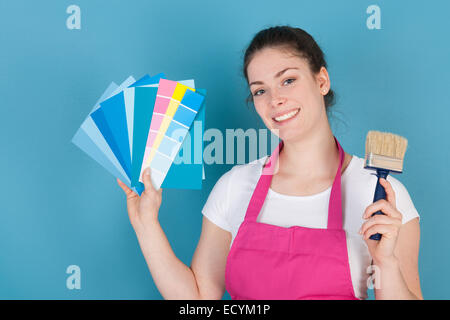 Woman with color samples against blue wall Stock Photo