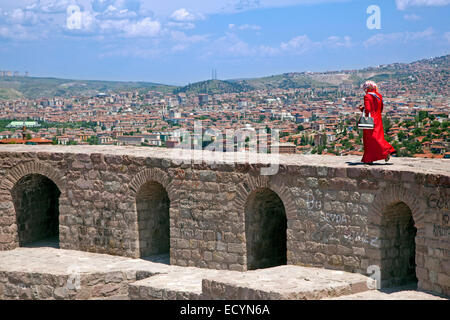Muslim woman dressed in Turkish Hijab style walking on the old citadel wall with view over the city Ankara, Turkey Stock Photo