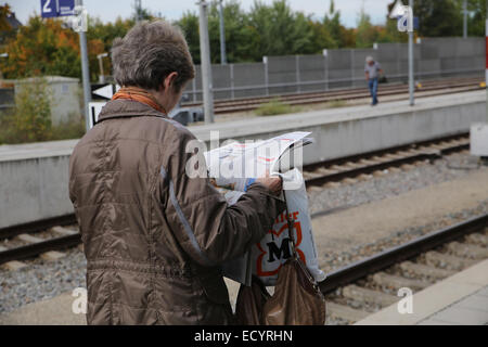 woman reading newspaper waiting train station Stock Photo