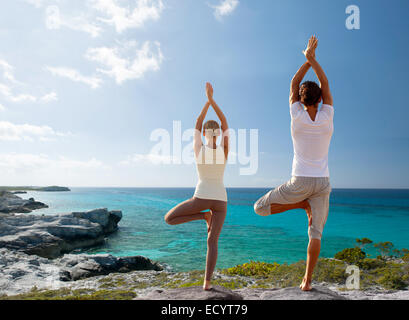 couple making yoga exercises on beach from back Stock Photo
