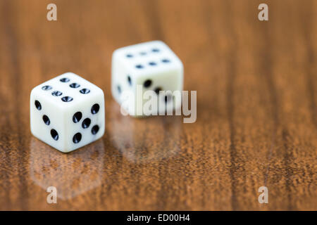 Two dice on a wooden background showing two sixes Stock Photo