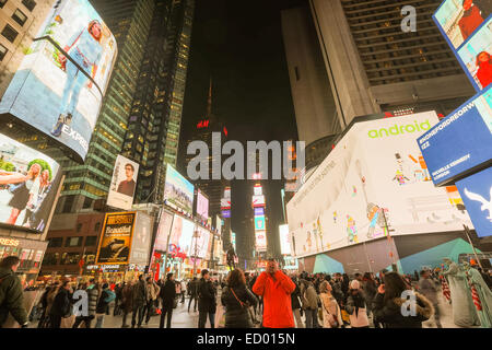 Pedestrians gather in Duffy Square part of Times Square along December 15, 2014 in New York City, NY. Stock Photo