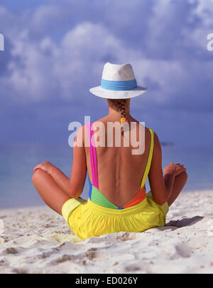 Young woman sitting on tropical beach, Kuda Bandos, Kaafu Atoll, Republic of Maldives Stock Photo