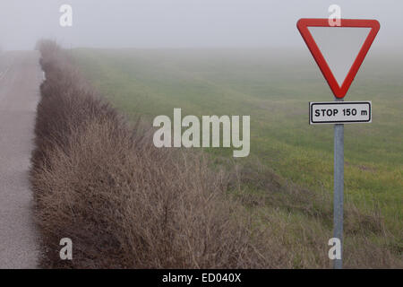 Metal pole with traffic signal yield sign in rural road next to Ahillones, Badajoz, Spain Stock Photo