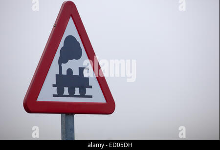 Metal pole with Railroad Level Crossing Sign without barrier a dense foggy day, in rural road next to Ahillones, Badajoz, Spain Stock Photo