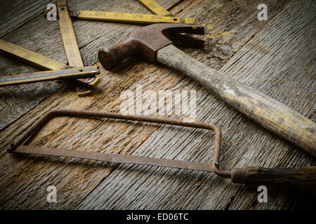 Hammer, Saw and Measuring Tape on Rustic Wood Background Stock Photo