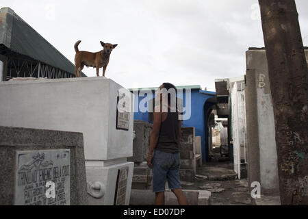 This cemetery in the heart of Pasay in Metro Manila, is the resting place for over 10,000 deceased people and some living ones. About ten cemetery caretakers and their families live there, in very poor conditions but still feeling safer among the graves than living on the outside as this poor neighbourhood is known for drugs and violence. They look after each other and fend of any squatters or intruders, especially males, to protect their children. 14th Dec, 2014. © Probal Rashid/ZUMA Wire/Alamy Live News Stock Photo