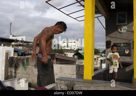 This cemetery in the heart of Pasay in Metro Manila, is the resting place for over 10,000 deceased people and some living ones. About ten cemetery caretakers and their families live there, in very poor conditions but still feeling safer among the graves than living on the outside as this poor neighbourhood is known for drugs and violence. They look after each other and fend of any squatters or intruders, especially males, to protect their children. 14th Dec, 2014. © Probal Rashid/ZUMA Wire/Alamy Live News Stock Photo