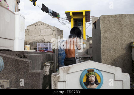 This cemetery in the heart of Pasay in Metro Manila, is the resting place for over 10,000 deceased people and some living ones. About ten cemetery caretakers and their families live there, in very poor conditions but still feeling safer among the graves than living on the outside as this poor neighbourhood is known for drugs and violence. They look after each other and fend of any squatters or intruders, especially males, to protect their children. 14th Dec, 2014. © Probal Rashid/ZUMA Wire/Alamy Live News Stock Photo