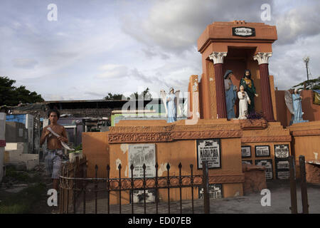 This cemetery in the heart of Pasay in Metro Manila, is the resting place for over 10,000 deceased people and some living ones. About ten cemetery caretakers and their families live there, in very poor conditions but still feeling safer among the graves than living on the outside as this poor neighbourhood is known for drugs and violence. They look after each other and fend of any squatters or intruders, especially males, to protect their children. 14th Dec, 2014. © Probal Rashid/ZUMA Wire/Alamy Live News Stock Photo