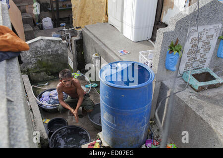 This cemetery in the heart of Pasay in Metro Manila, is the resting place for over 10,000 deceased people and some living ones. About ten cemetery caretakers and their families live there, in very poor conditions but still feeling safer among the graves than living on the outside as this poor neighbourhood is known for drugs and violence. They look after each other and fend of any squatters or intruders, especially males, to protect their children. 14th Dec, 2014. © Probal Rashid/ZUMA Wire/Alamy Live News Stock Photo