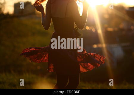 Young woman dancing in a meadow at sunset Stock Photo