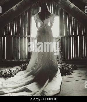 Rear view of young woman in a wedding dress looking out of a window Stock Photo