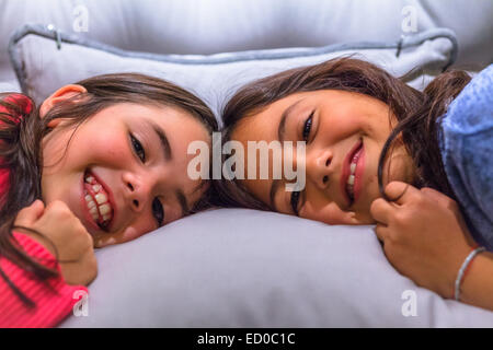 Portrait of two smiling girls lying on a bed Stock Photo