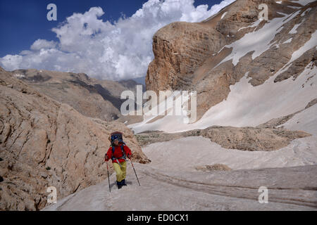 The mountaineer-woman raises up across rocks covered with deep snow. Woman is dressed in bright clothes. Stock Photo