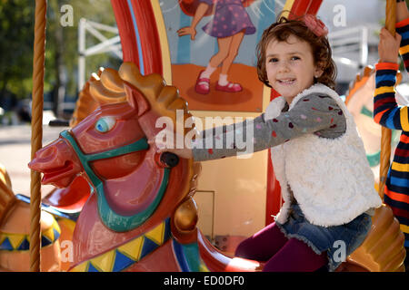 Beautiful little girl (4-5) riding carousel horse Stock Photo