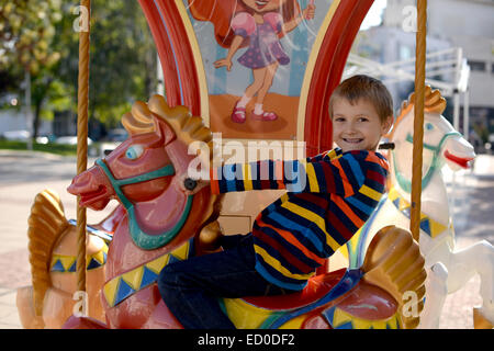 Little boy (6-7) riding carousel horse Stock Photo