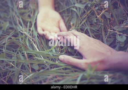 Man and woman lying in grass holding hands Stock Photo