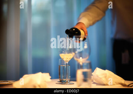 Cropped shot of man in room pouring white wine in wineglass Stock Photo